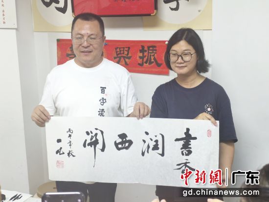 一凡(左)赠书法作品《书香润西关》。主办方供图 一凡(左)赠书法作品《书香润西关》。主办方供图